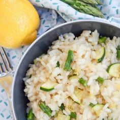 a bowl filled with rice and asparagus on top of a table next to a lemon