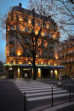 the building is lit up at night and it's lights shine brightly on the street