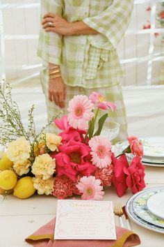 the table is set with pink and yellow flowers