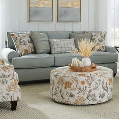 a living room filled with furniture and pillows on top of a carpeted floor next to windows