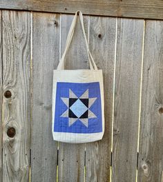 a blue and white quilted bag hanging on the side of a wooden fence,