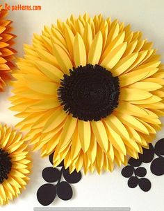 three sunflowers made out of paper on a white surface with black circles around them