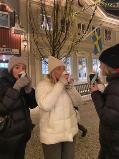 two women standing outside drinking from cups