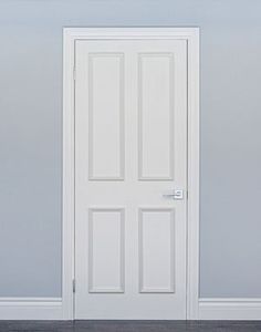 an empty room with a white door and wood flooring on the side, in front of a gray wall