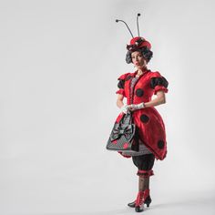 a woman dressed in red and black with a lady bug on her head