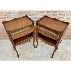 two wooden side tables sitting next to each other in front of a brick wall and floor