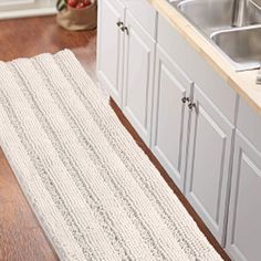 a kitchen area with sink, dishwasher and rug on the floor in front of it