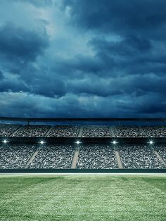 an empty soccer stadium filled with lots of seats under a dark sky full of clouds