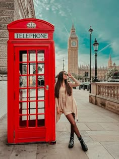 a woman standing next to a red phone booth