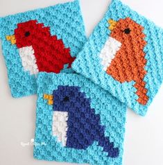 two crocheted coasters with different colored birds on them, one is blue and the other is orange