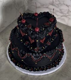 a three tiered cake decorated with black and red decorations