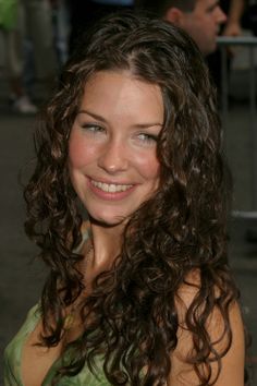 a woman with long curly hair smiling at the camera