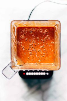 a blender filled with liquid sitting on top of a white counter next to a wire