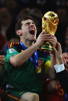 a soccer player is holding up the world cup in his hands and yelling at it