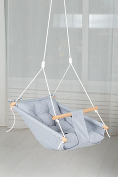 a blue hammock chair hanging from a white ceiling in front of a window