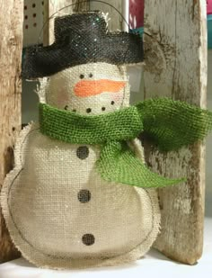 a snowman made out of burlock and fabric with a green scarf around his neck