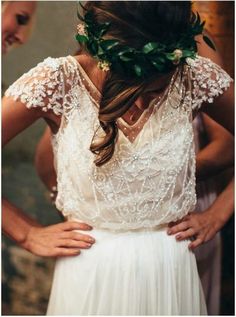 a woman wearing a white dress with flowers in her hair is standing next to another woman