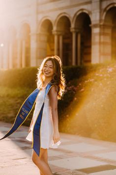 a woman is walking down the street wearing a blue and white graduation sash