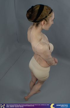 a woman in a tan bodysuit is posing for the camera with her hands on her hips