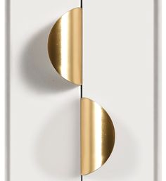 two gold circles on a white wall next to each other in the shape of an object