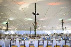 the tables are set with white linens and yellow chairs for an elegant wedding reception