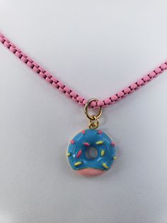 A donut necklace, this necklace has a donut as a pendant and the chain is in pink color. Chain Color: Pink Charm: Donut Chain Style: Snake Style With Extensor More Information? Contact Page or (939)349-2859 Trendy Pink Metal Choker, Pink Round Charm Necklace With Adjustable Chain, Pink Chain Choker Necklace, Trendy Pink Round Necklace, Trendy Round Pink Necklaces, Trendy Pink Round Necklaces, Trendy Pink Clavicle Chain Necklace, Trendy Pink Short Chain Necklace, Cute Pink Jewelry With Chain Detail