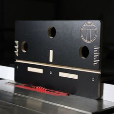 a close up of a machine with holes in the center and two red wires running through it