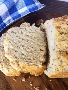 a loaf of bread sitting on top of a wooden cutting board next to a blue and white checkered pillow