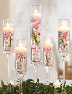 candles are lined up on a table with greenery