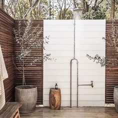 an outdoor shower in the middle of a wooden deck with two planters next to it