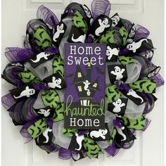 a halloween wreath with purple and green mesh, black and white decorations and ghost's on the front door