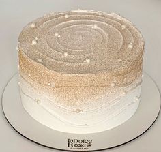 a cake with white frosting and gold sprinkles sits on a plate