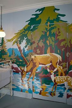 a baby crib in front of a painted wall with deer and trees on it