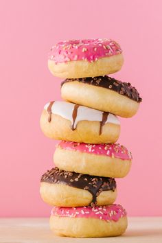 five donuts stacked on top of each other with pink frosting and sprinkles