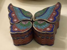 two colorful butterfly shaped boxes sitting on top of a white table next to a plate