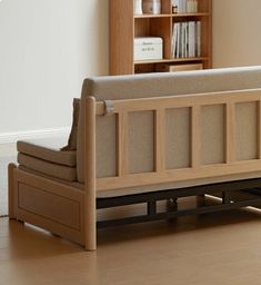 a couch sitting on top of a hard wood floor next to a book shelf filled with books