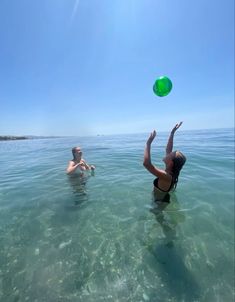 two people playing with a frisbee in the ocean on a sunny day,