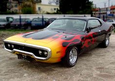 a yellow and red car with flames painted on it's hood is parked in a parking lot