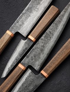 three knives with wooden handles on a black surface