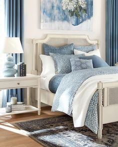 a bedroom with blue curtains and white bedding