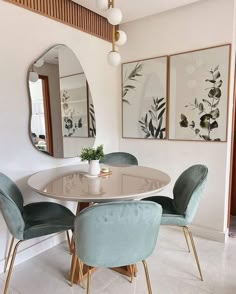 a dining room table with four chairs and a round mirror on the wall above it