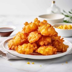 a plate full of fried corn on the cob next to bowls of dipping sauce