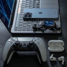 an open laptop computer sitting on top of a table next to ear buds and headphones