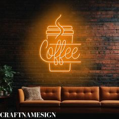 a neon coffee sign on the side of a brick wall next to a brown couch