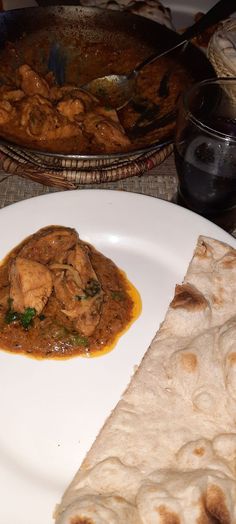 a white plate topped with food next to a bowl of soup and pita bread