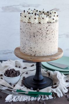 a cake with white frosting and chocolate chips sitting on top of a wooden table