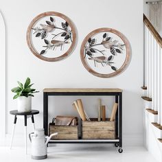 there are two circular paintings on the wall next to a shelf with books and vases