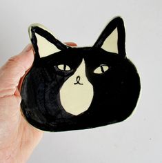 a hand holding a black and white ceramic cat