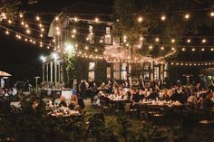 a group of people sitting at tables under string lights