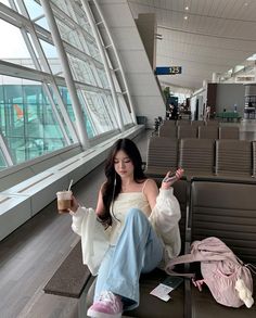 a woman sitting in an airport holding a drink